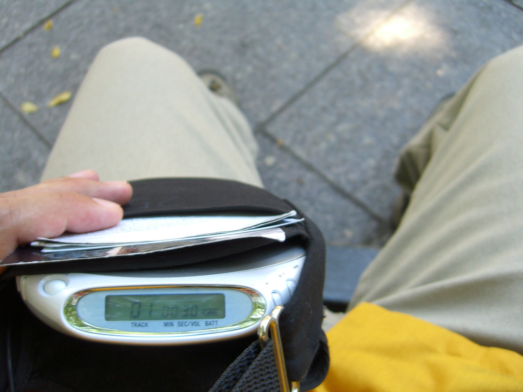 the lap of a seated man wearing khaki pants holding a diskman. on the screen of the diskman is "Track 01" and the timestamp "00:30"